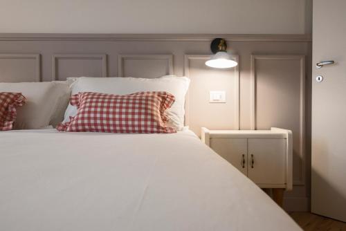 a white bed with a red and white pillow on it at Villa Mariolino in San Pellegrino Terme