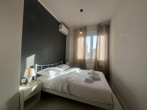 1 dormitorio con cama blanca y ventana en Ladadika Fine Living en Tesalónica