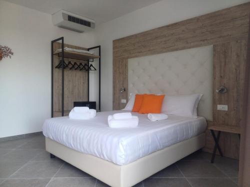 a bedroom with a large bed with white sheets and orange accents at Domo Annalisa in Àrbatax