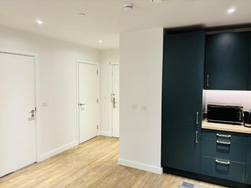 a kitchen with blue cabinets and white walls at Your London Escape Luxurious 1 Bedroom Apartment in London