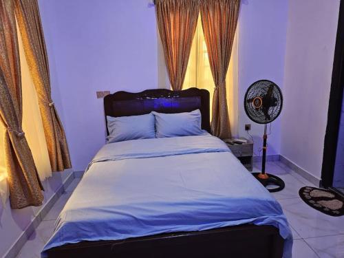 1 dormitorio con 1 cama y ventilador en Glory Apartment en Ibadán