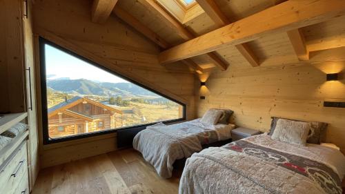 two beds in a room with a large window at Chalet Mont-Reve in Font-Romeu-Odeillo-Via