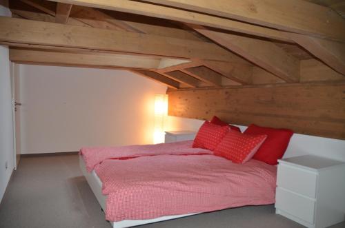 ein Schlafzimmer mit einem Bett mit roten Kissen darauf in der Unterkunft Alpine Lodge Parc Linard in Lenzerheide