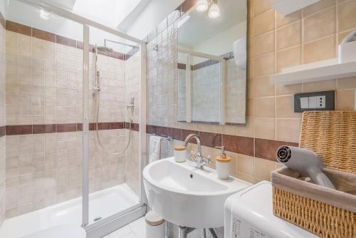 La salle de bains est pourvue d'un lavabo blanc et d'une douche. dans l'établissement Fly To Home Siena Centre, à Sienne