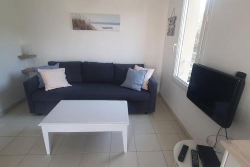 - un salon avec un canapé bleu et une table blanche dans l'établissement Studio en résidence avec piscine - 2820, à Soulac-sur-Mer
