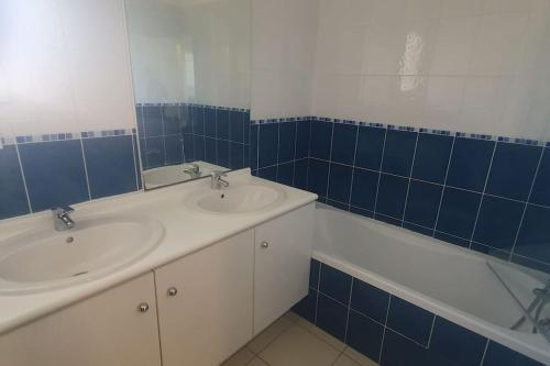 een blauwe en witte badkamer met 2 wastafels en een bad bij Studio en résidence avec piscine - 2820 in Soulac-sur-Mer