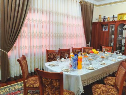 mesa de comedor con mantel y sillas blancas en ZARIN Guest House B&B, en Bukhara