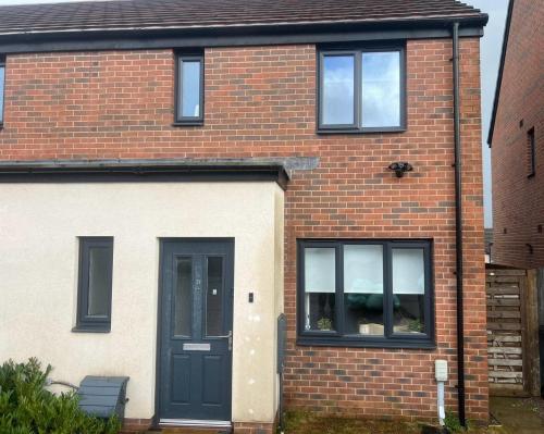 une maison en briques avec une porte et des fenêtres noires dans l'établissement Village House Cardiff - Close to A48 and M4, à Cardiff