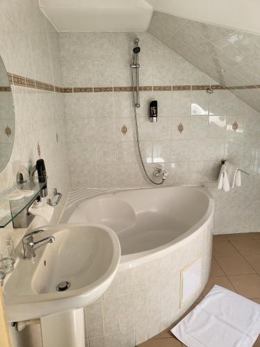 a bathroom with a white tub and a sink at Hotel Margit in Trenčianske Teplice