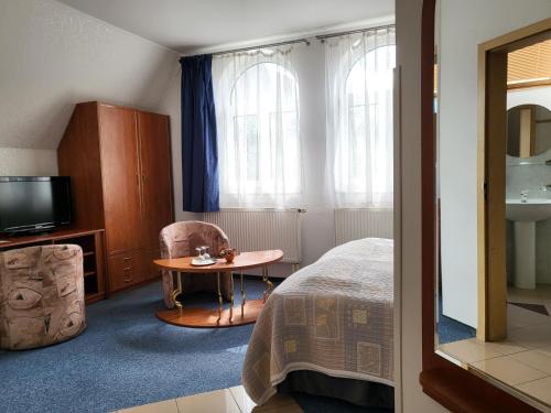 Schlafzimmer mit einem Bett, einem Tisch und einem TV in der Unterkunft Hotel Margit in Trenčianske Teplice