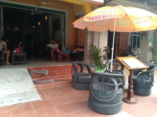 ein Regenschirm und zwei Stühle und ein Tisch und einige Leute in der Unterkunft Birds Nest 2.0 in Kampot