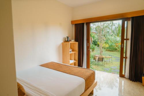 um quarto com uma cama e uma grande janela em Artha Cottages em Sidomukti