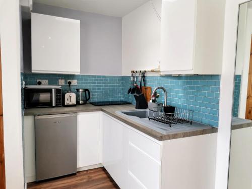a white kitchen with a sink and a microwave at Harbour House Studio, Porlock Weir in Culbone