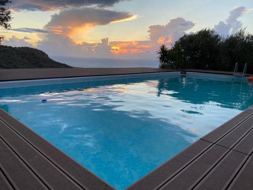 una piscina con puesta de sol en el fondo en Villa in campagna con piscina, en San Fratello