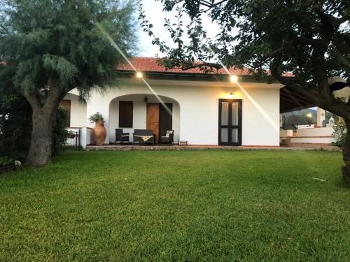 una pequeña casa blanca con un patio verde en Villa in campagna con piscina, en San Fratello