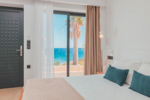 een slaapkamer met een bed en uitzicht op de oceaan bij Plakakia Luxury Apartments in Makry Gialos
