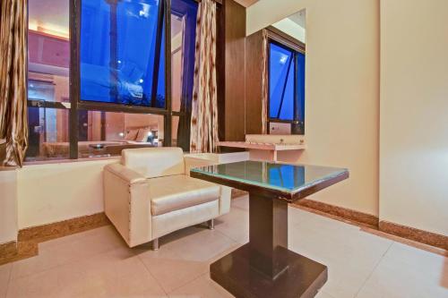 einen Tisch und einen Stuhl in einem Zimmer mit Fenstern in der Unterkunft Collection O Hotel My Stay Inn II in Jaipur