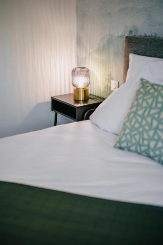 a bed with a lamp on a side table at Résidence Les Charmes in Boofzheim