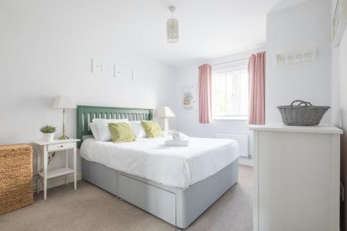 a white bedroom with a bed with white sheets and yellow pillows at Detached 4-Bed home - Idyllic Village in Cambridge