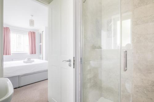 La salle de bains blanche est pourvue d'une douche et d'un lavabo. dans l'établissement Detached 4-Bed home - Idyllic Village, à Cambridge