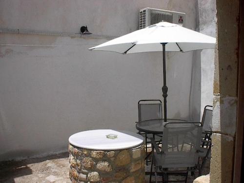 a table and chairs with a white umbrella at Goulas Traditional Guesthouse in Monemvasia