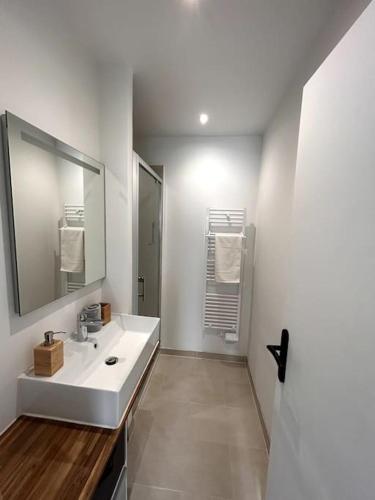 ein weißes Badezimmer mit Waschbecken und Spiegel in der Unterkunft Appartement 4/6 personnes - Cornimont in Cornimont