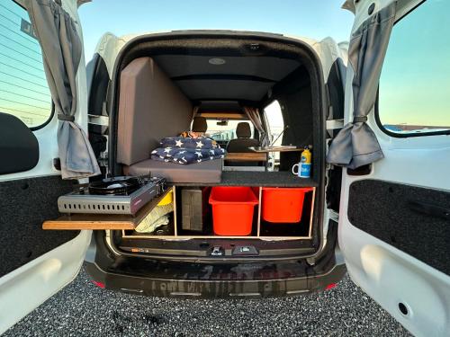 una parte trasera abierta de una furgoneta con cama y sillas en KúKú Campers - Campervans en Keflavík