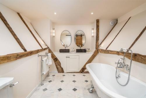 a bathroom with a tub and two mirrors at Pass the Keys Merlin’s stables-country retreat in Brill