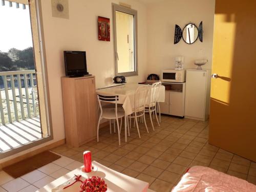 Il comprend un salon avec une table et une cuisine avec un balcon. dans l'établissement Studio en front de mer - 3256, à Soulac-sur-Mer