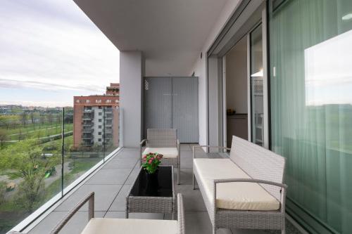 a balcony with two chairs and a table with flowers at Terminal Tower 601 - San Cristoforo M4 in Milan