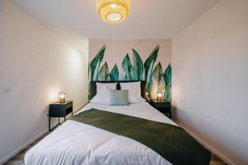 een slaapkamer met een groot bed met groene planten aan de muur bij Résidence Les Charmes in Boofzheim