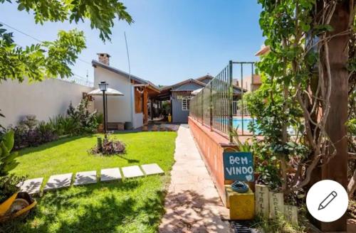 un patio con piscina y un cartel en el césped en Pousada e Hotel Italian Garden House, en Campo Grande