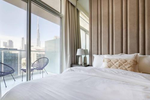 a bedroom with a white bed and a large window at Burj Khalifa View With 5star Flatwalk Dubai Mall in Dubai