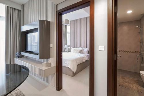 a bedroom with a bed and a tv and a bathroom at Burj Khalifa View With 5star Flatwalk Dubai Mall in Dubai