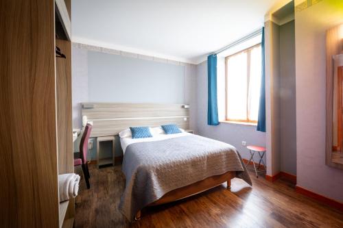 a bedroom with a bed and a desk and a window at Logis hôtel Au Relais Nivernais in Nevers