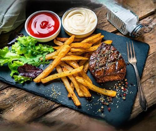 a plate of food with a steak and french fries at Akbar’s Hotel in Dhaka