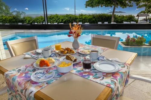 uma mesa com comida para o pequeno almoço ao lado de uma piscina em Ingleses Praia Hotel em Florianópolis