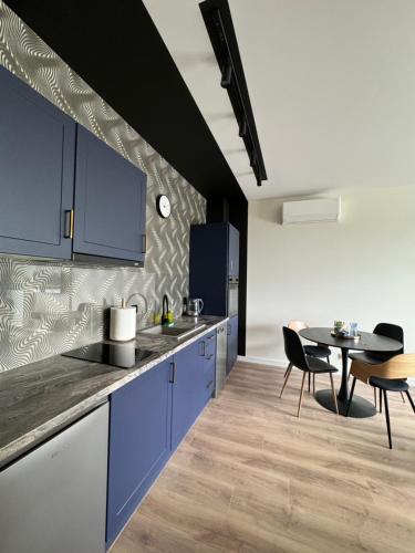 eine Küche mit blauen Schränken und einem Tisch mit Stühlen in der Unterkunft Apartament Pileckiego 7b/37 in Suwałki