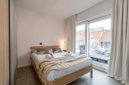um quarto com uma cama e uma grande janela em Sunny apartment in Knokke-Heist with big terrace em Knokke-Heist