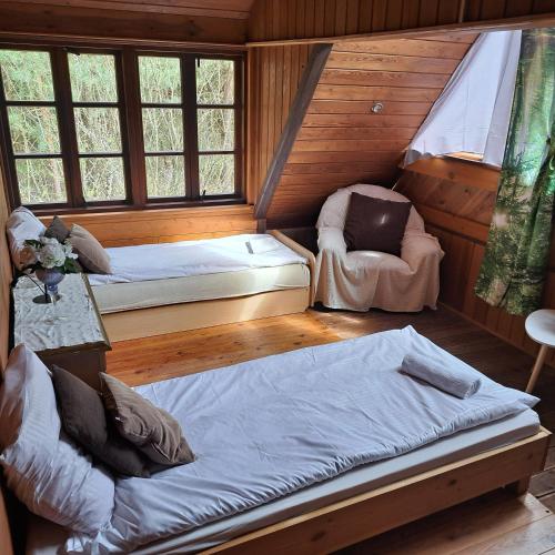 una habitación con 2 camas y una silla en una cabaña en Domek wycieczkowy 