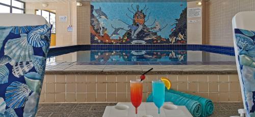 two cocktails on a table in front of a swimming pool at Ingleses Praia Hotel in Florianópolis