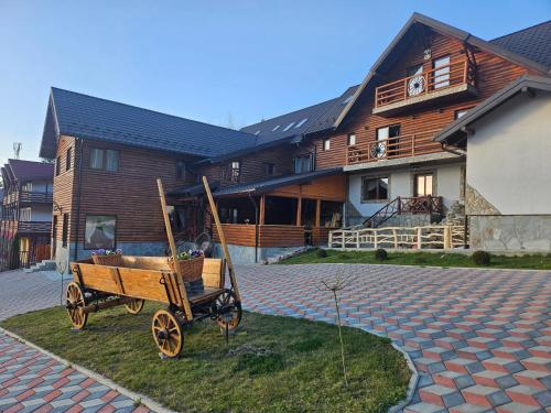 a wooden cart in front of a house at Pensiunea Ana Maria Durau in Durau