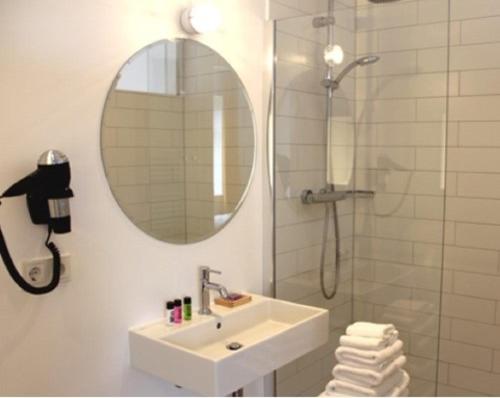 een badkamer met een wastafel en een douche met een spiegel bij Der Charlottenhof in Ahrenshoop