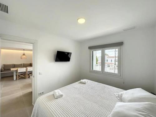a white bedroom with a bed and a window at Ses Salines Apartments SAranalet in Fornells
