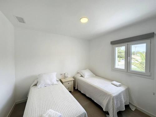 two beds in a room with a window at Ses Salines Apartments SAranalet in Fornells