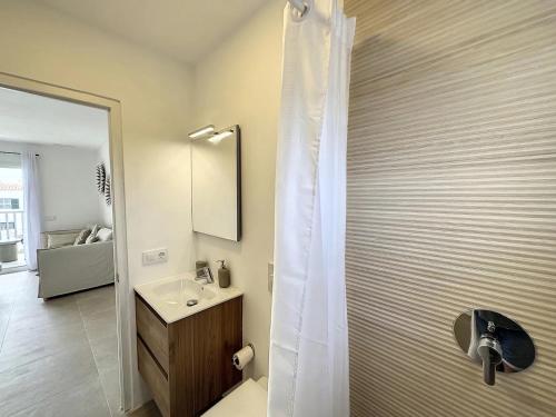 a bathroom with a shower with a sink and a mirror at Ses Salines Apartments SAranalet in Fornells