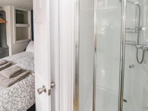 a shower with a glass door next to a bed at Penpwmp in Newport