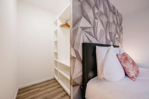 a bedroom with a bed with a geometric headboard at Résidence Les Charmes in Boofzheim