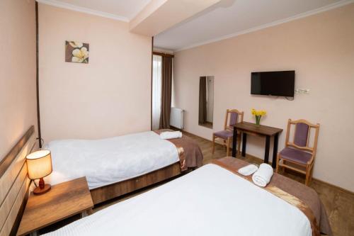 a hotel room with two beds and a television at Guest House Kavkasioni 33 in Tʼelavi
