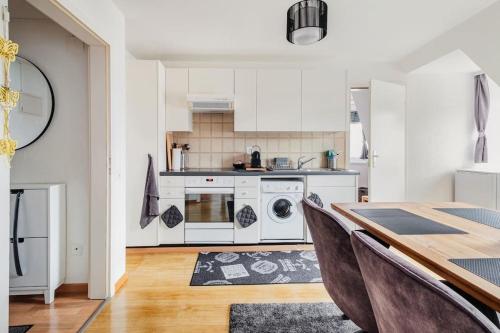 a kitchen with white cabinets and a table with chairs at Charmante Wohnung an beliebter, urbaner Lage in Zurich